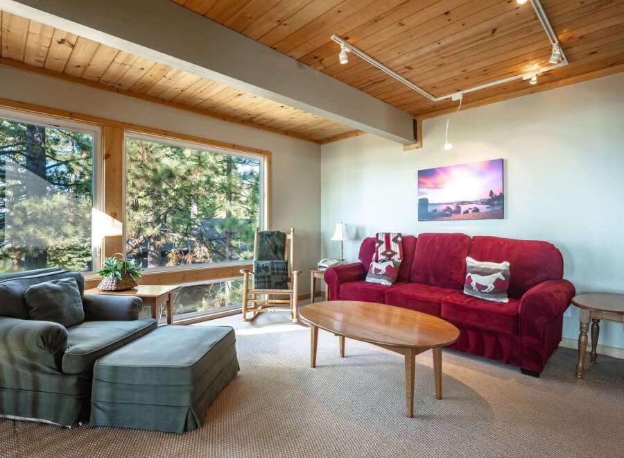 Experience cozy living in this inviting living room, featuring a plush red sofa and a comfortable armchair with an ottoman.