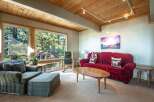 Experience cozy living in this inviting living room, featuring a plush red sofa and a comfortable armchair with an ottoman.