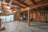 Discover ample storage and functionality in this spacious garage, featuring overhead cabinets and a convenient refrigerator.