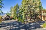 Nestled amongst towering pine trees, this stunning property offers a picturesque setting with a glimpse of a serene lake in the distance.