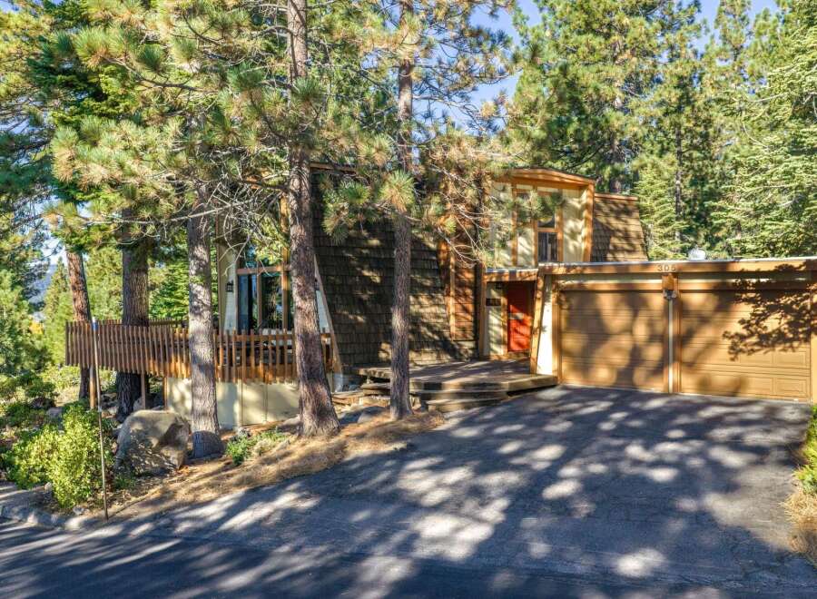 Nestled among tall pine trees, this charming home offers a unique A-frame design with a warm, inviting exterior.