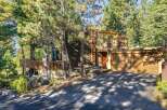 Nestled among tall pine trees, this charming home offers a unique A-frame design with a warm, inviting exterior.