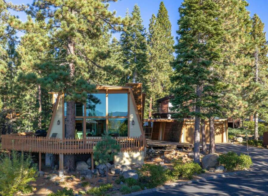 Nestled amongst towering pine trees, this A-frame home offers stunning lake views through its expansive floor-to-ceiling windows.