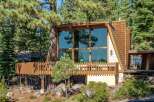 Nestled amongst tall pine trees, this unique A-frame home offers stunning natural views through its expansive floor-to-ceiling windows.