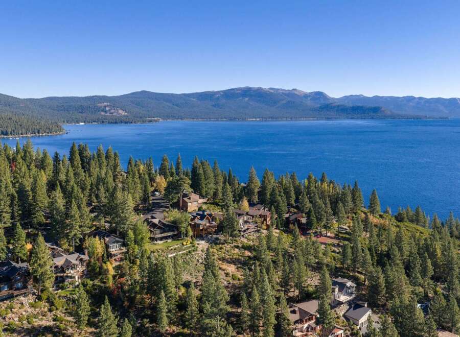 Nestled amidst a lush pine forest, this stunning property offers breathtaking panoramic views of a vast, shimmering blue lake and distant mountains.