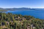 Nestled amidst a lush pine forest, this stunning property offers breathtaking panoramic views of a vast, shimmering blue lake and distant mountains.