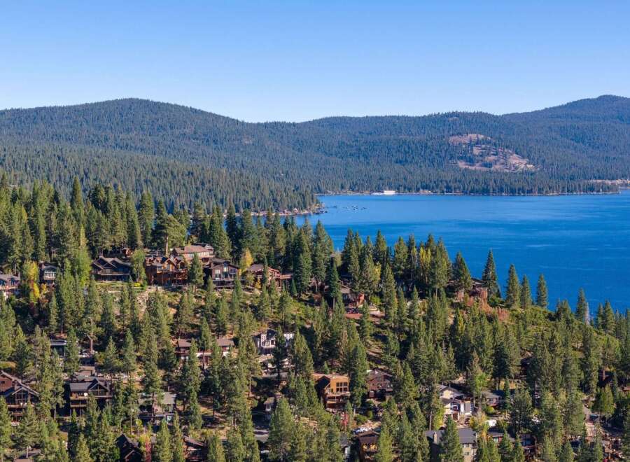Discover luxury living nestled amidst the towering pines with breathtaking views of a pristine blue lake.