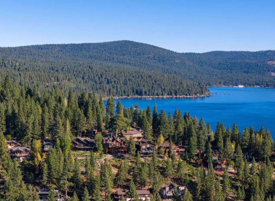 Experience luxury living nestled amidst the towering pines with breathtaking views of a pristine blue lake.