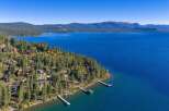 Experience luxury living with this stunning aerial view of lakeside homes nestled among tall pine trees.