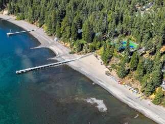 Experience lakeside luxury with this stunning aerial view of a private beach and pier, perfect for enjoying the crystal-clear waters.