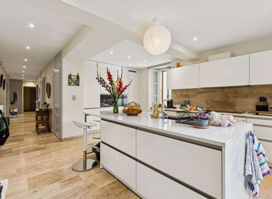 Step into this modern and spacious kitchen, featuring sleek white cabinetry and a large central island perfect for meal preparation and casual dining.