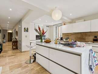 Step into this modern and spacious kitchen, featuring sleek white cabinetry and a large central island perfect for meal preparation and casual dining.