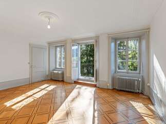 Bathed in natural light, this charming room features a beautifully patterned hardwood floor that catches the sun's rays.