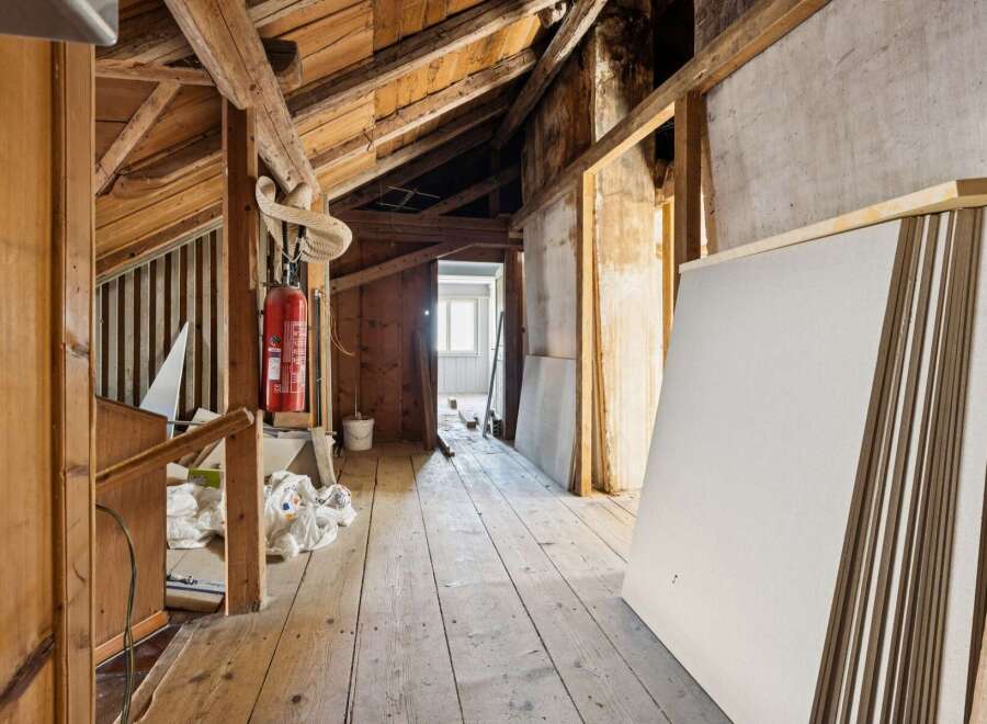 This unfinished attic space offers a blank canvas for renovation, featuring exposed wooden beams and a rustic charm.