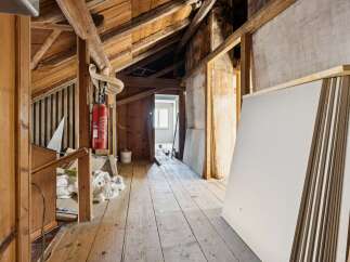 This unfinished attic space offers a blank canvas for renovation, featuring exposed wooden beams and a rustic charm.