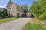 Discover this charming property featuring a rustic stone building with traditional wooden accents and arched windows.