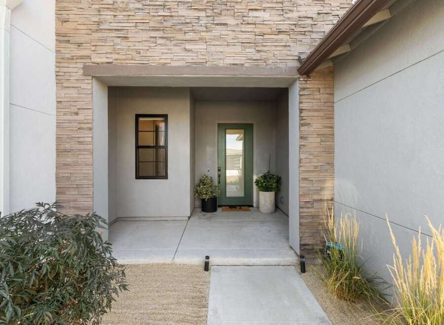 Welcome guests to this modern home with a striking stone facade and a welcoming covered entryway.