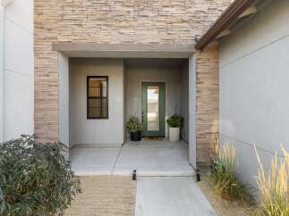 Welcome guests to this modern home with a striking stone facade and a welcoming covered entryway.