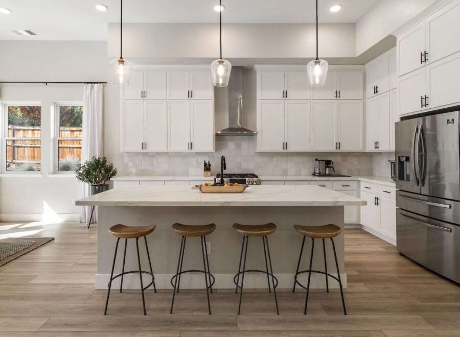 This modern kitchen boasts sleek white cabinetry and a stunning marble island, perfect for entertaining.