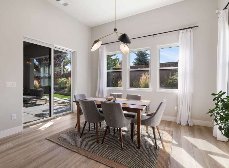 This dining room features a modern wooden dining table with six upholstered chairs, all set on a textured rug.