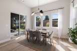 This dining room features a modern wooden dining table with six upholstered chairs, all set on a textured rug.