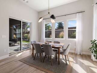 This dining room features a modern wooden dining table with six upholstered chairs, all set on a textured rug.