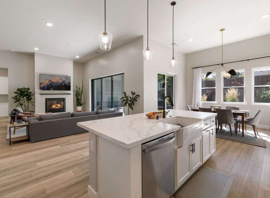 Experience modern living in this open-concept home, featuring a spacious living area with a cozy fireplace and a large TV.