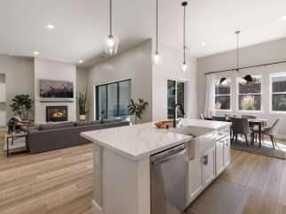 Experience modern living in this open-concept home, featuring a spacious living area with a cozy fireplace and a large TV.