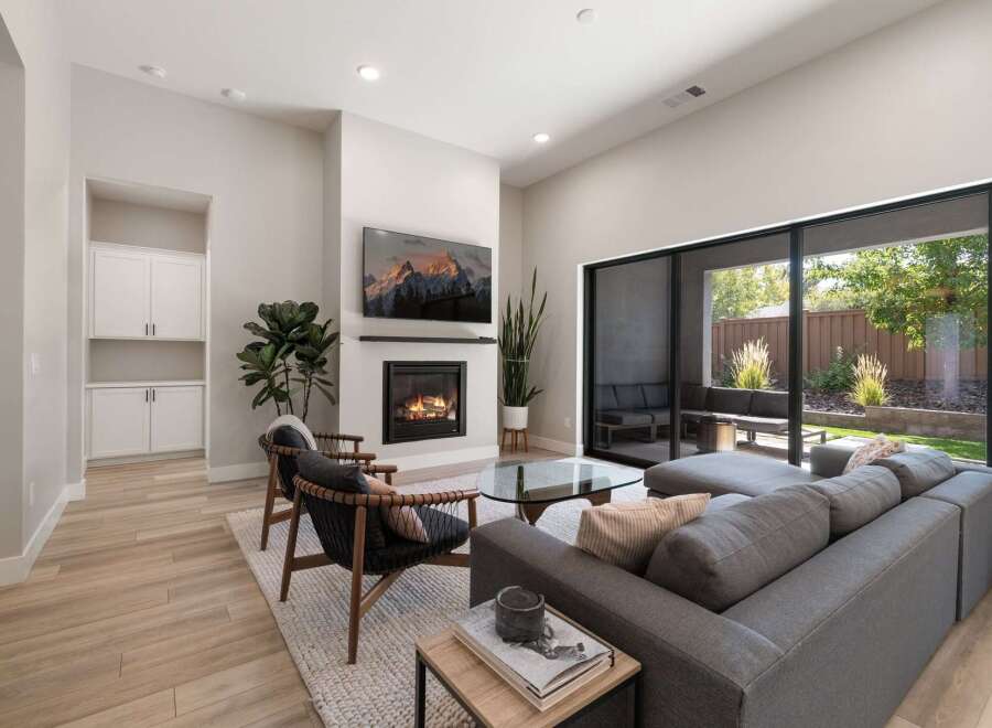 Experience modern living in this stunning living room featuring a cozy fireplace and a large sliding glass door that opens to a beautiful outdoor patio.