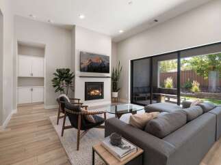Experience modern living in this stunning living room featuring a cozy fireplace and a large sliding glass door that opens to a beautiful outdoor patio.