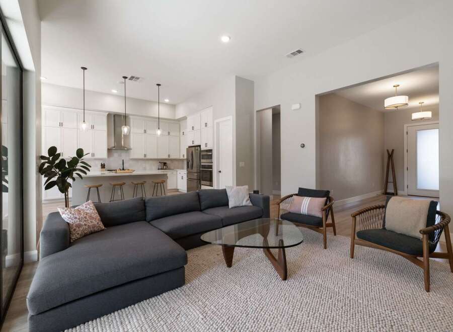 Experience modern living in this open-concept home featuring a sleek white kitchen with a large island and pendant lighting, seamlessly flowing into a spacious living area.