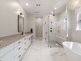 Experience luxury in this stunning master bathroom, featuring a spacious walk-in shower with marble tile and a built-in bench.