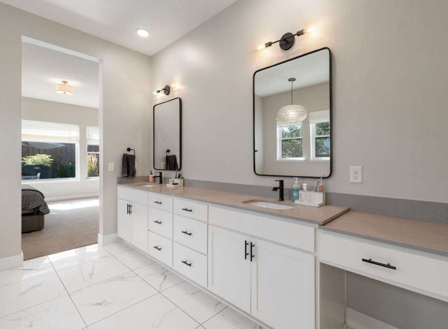 This modern bathroom features a spacious double vanity with sleek black hardware and a gray quartz countertop.