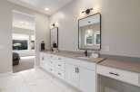 This modern bathroom features a spacious double vanity with sleek black hardware and a gray quartz countertop.
