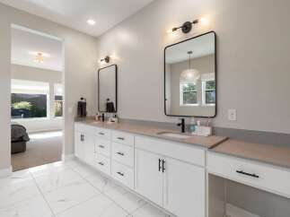 This modern bathroom features a spacious double vanity with sleek black hardware and a gray quartz countertop.