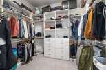 Discover ample storage in this spacious walk-in closet, featuring custom shelving and multiple hanging rods to organize your wardrobe.