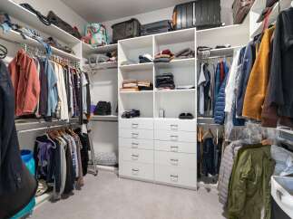 Discover ample storage in this spacious walk-in closet, featuring custom shelving and multiple hanging rods to organize your wardrobe.