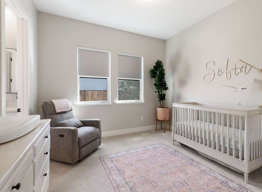 This charming nursery features a comfortable gray recliner with a pink throw, perfect for late-night feedings.