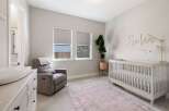 This charming nursery features a comfortable gray recliner with a pink throw, perfect for late-night feedings.