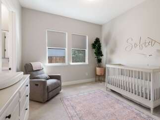 This charming nursery features a comfortable gray recliner with a pink throw, perfect for late-night feedings.