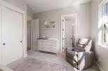 This charming nursery features a comfortable gray recliner with a pink throw, perfect for soothing a baby.