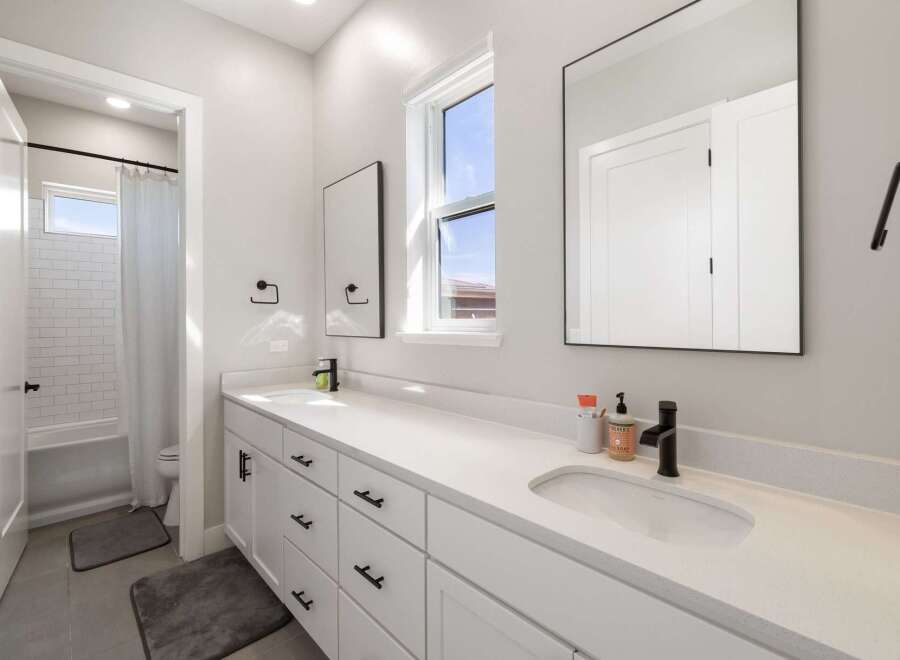 This modern bathroom features a spacious white vanity with dual sinks and ample storage, perfect for any family.