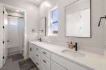 This modern bathroom features a spacious white vanity with dual sinks and ample storage, perfect for any family.