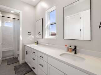 This modern bathroom features a spacious white vanity with dual sinks and ample storage, perfect for any family.