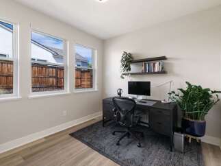 This home office features a modern dark wood desk with a computer, headphones, and a sleek desk lamp.