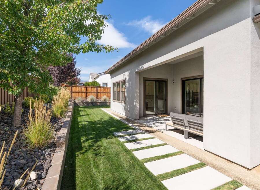 Enjoy outdoor living in this beautifully landscaped backyard featuring a lush green lawn and a modern concrete paver pathway.