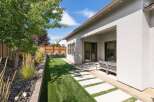Enjoy outdoor living in this beautifully landscaped backyard featuring a lush green lawn and a modern concrete paver pathway.