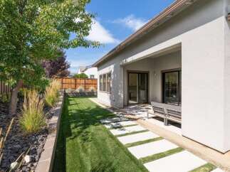 Enjoy outdoor living in this beautifully landscaped backyard featuring a lush green lawn and a modern concrete paver pathway.