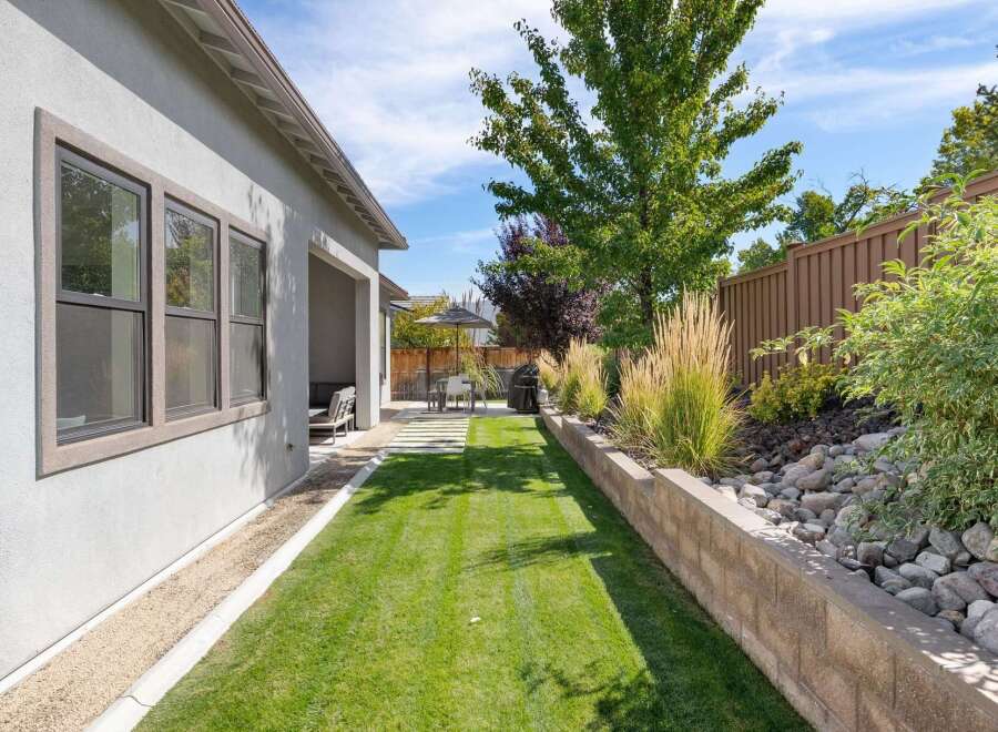 Enjoy outdoor living in this beautifully landscaped backyard, featuring a lush green lawn perfect for recreation and a covered patio area for shaded relaxation.