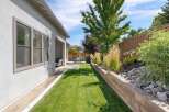 Enjoy outdoor living in this beautifully landscaped backyard, featuring a lush green lawn perfect for recreation and a covered patio area for shaded relaxation.